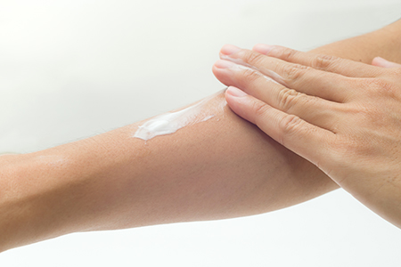 Applying eczema control cream on fore arm rash